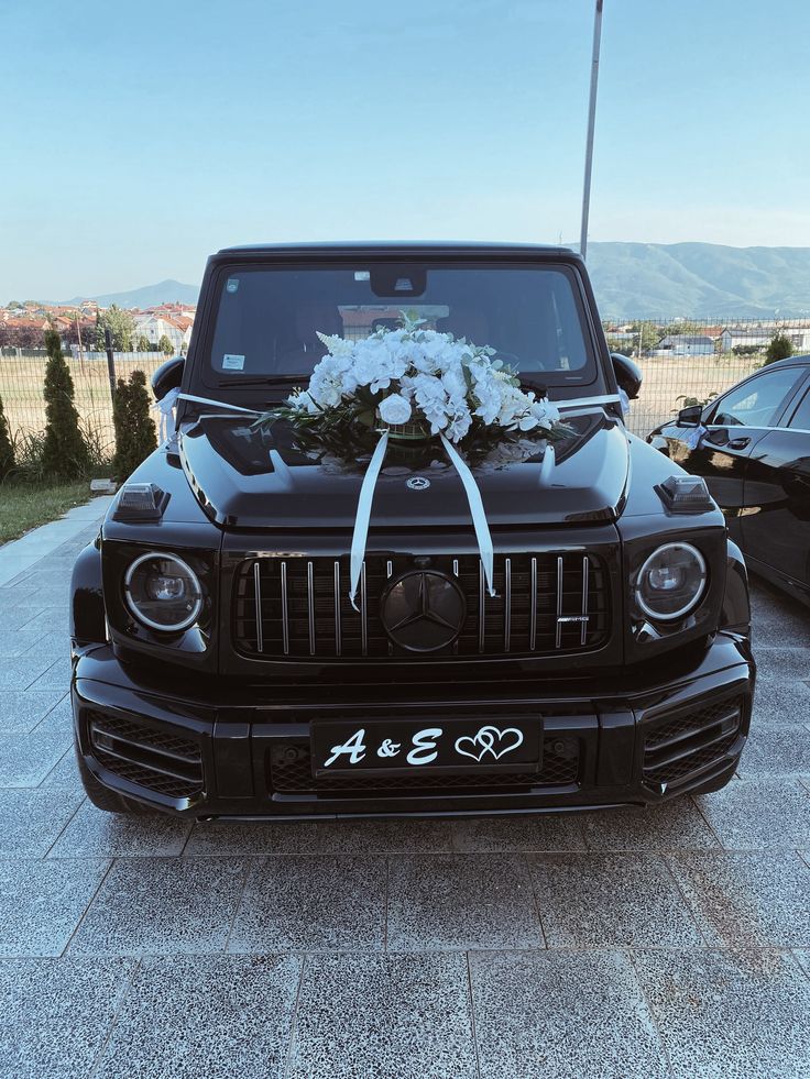 Black wedding SUV decorated with white flowers and ribbon on the bonnet