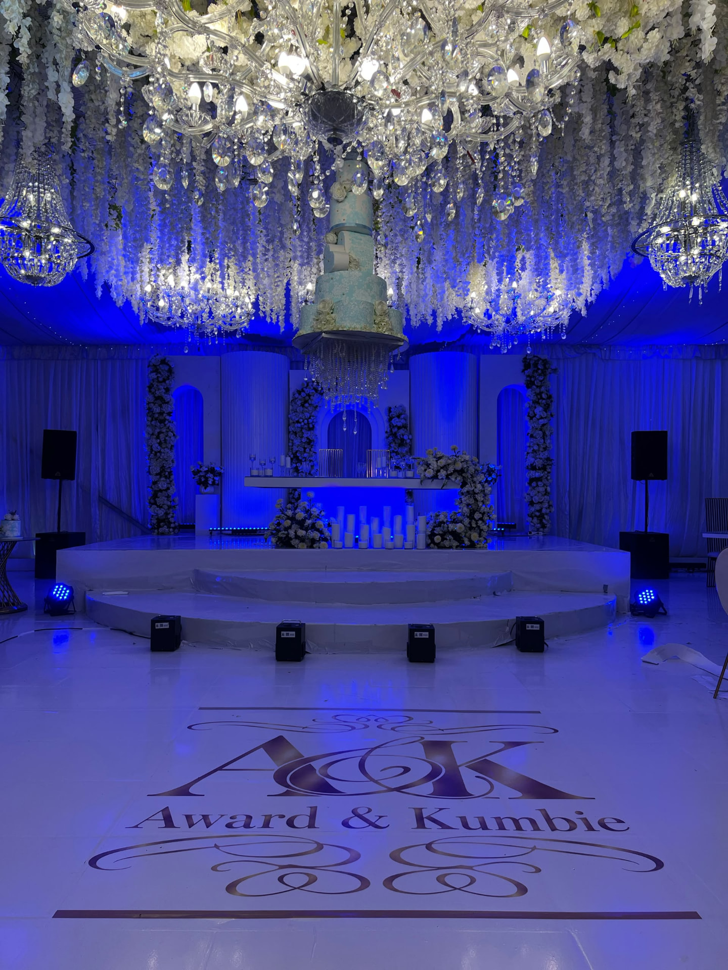 Blue-lit reception stage with a personalised vinyl floor wrap