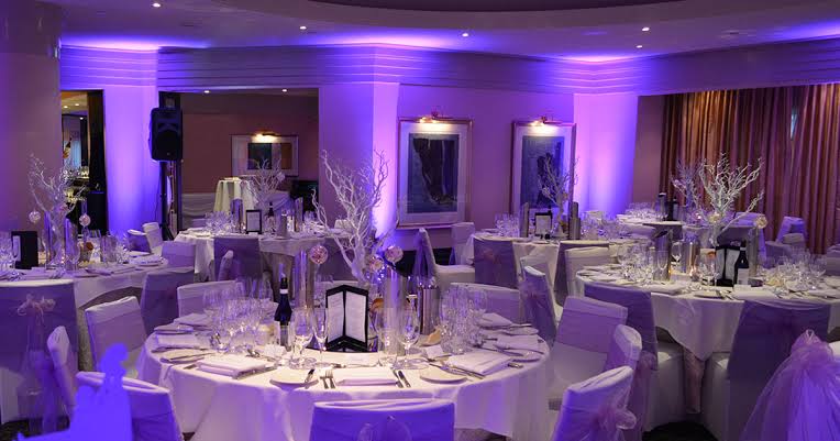 Purple-lit reception room with banquet tables and mood lighting