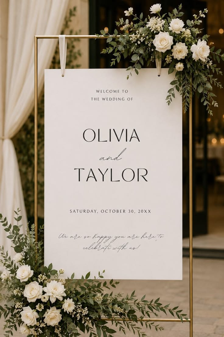 Personalised hanging wedding welcome board on a gold frame with white flowers and greenery