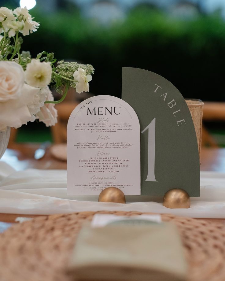 Arched wedding menu paired with a sage green table number