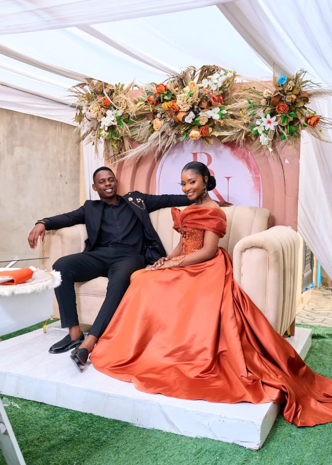 Brendon and Naomi seated beneath the floral roora arch in Harare