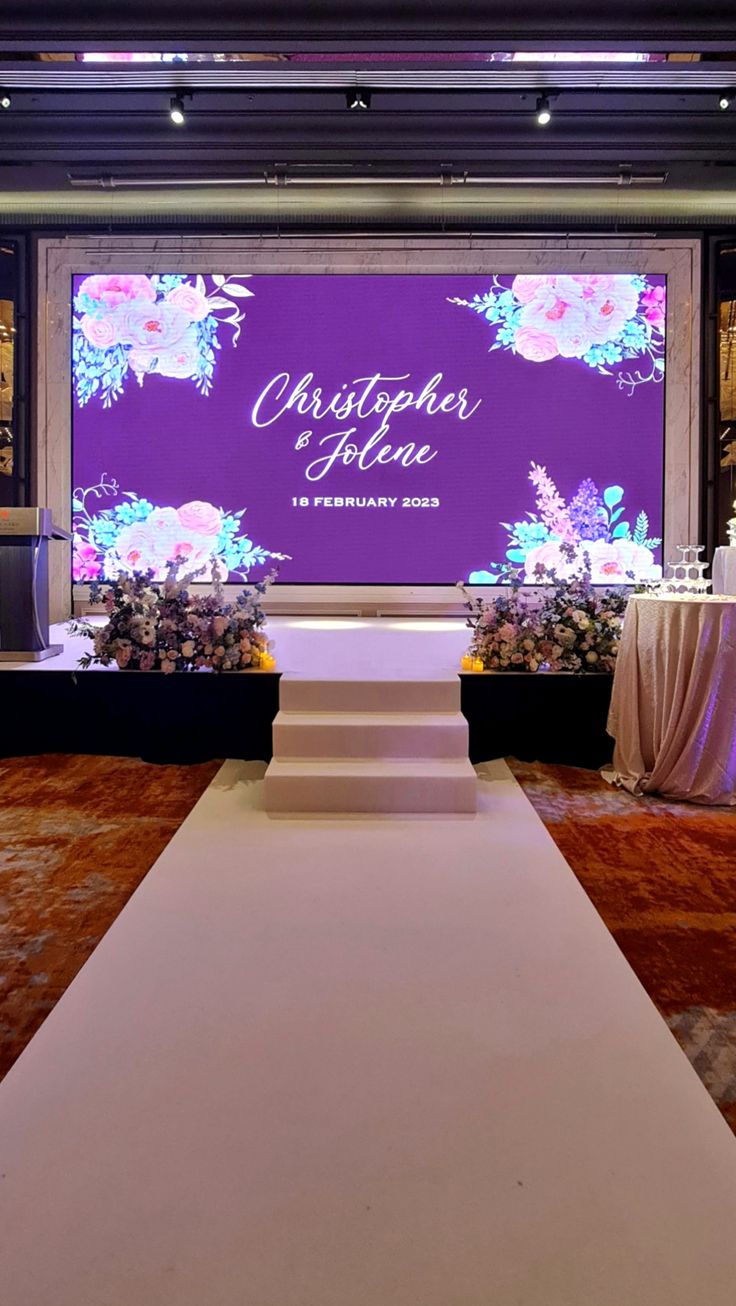 Wedding stage with a large LED screen showing the couple's names and flowers